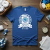 Graphic of a washing machine with "0000" displayed, surrounded by gears and a banner, on a blue t-shirt
