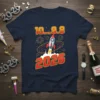 10...9.8 2026 countdown text with a rocket launching and fireworks graphic on a navy blue t-shirt