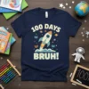 100 Days Bruh! T-Shirt with a rocket blasting off, books, and planets. Features the text "100 DAYS BRUH!" in bold