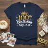 Navy blue t-shirt with gold and white text reading "100th Birthday SQUAD" and a crown graphic, perfect for a milestone