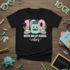100th Day of School vibes t-shirt with a cute blue monster, graduation cap, books, and pencils. Features the number 100