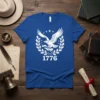 Blue t-shirt featuring a white eagle with banner, wreath, and the year 1776