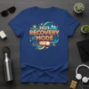 2023 Recovery Mode On graphic t-shirt design with mountains, sun, and book symbols