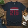 Dark navy t-shirt with bold red "215" number and a red and white Philadelphia skyline graphic above it