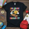 2nd Grade Nailed It! text with a cartoon star trophy and rainbow graphic on a black t-shirt