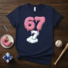 The number 67 designed as pink frosted donuts with sprinkles, with a baseball stitching '7' emerging from clouds below