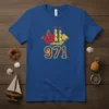 Blue t-shirt featuring the number 971 with a yellow outline, a yellow sailing ship, and a red hibiscus flower