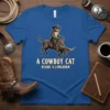 A Cowboy Cat Riding a Longhorn T-Shirt featuring a cat in a cowboy hat on a bull, text reads "A