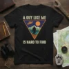 A Guy Like Me Is Hard To Find t-shirt featuring Bigfoot, UFO, and mountains graphic in a triangle design