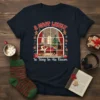 A Most Likely To Stay In His Room Christmas T-Shirt featuring a cozy room scene with a Christmas tree and