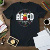 ABCD Teacher Tour quote with apple graphic on a black t-shirt, inspired by AC/DC logo