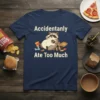 Accidentanly Ate Too Much t-shirt with a cartoon raccoon sitting with snacks and a donut, white text