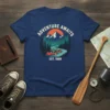Adventure Awaits Est. 1988 text with a canoe scene on a navy t-shirt, featuring mountains and trees