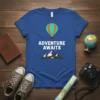 Adventure Awaits text with hot air balloon and mountain graphic on a blue t-shirt, ideal for travelers