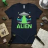 Navy blue t-shirt with the word ALIEN in large green text, featuring a cartoon UFO with a bright green beam