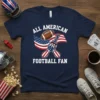 All American Football Fan text with USA flag and football on a navy t-shirt, featuring a hand in a foam