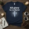 Navy blue t-shirt with white text "All glory be to Christ" and a light blue cross emblem with radiating lines