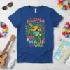 Blue t-shirt with "Aloha Maui Hawaii" text and a central sea turtle graphic surrounded by tropical flowers and surfboards