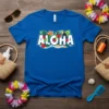 Blue t-shirt with white text "Aloha" surrounded by tropical flowers, leaves, and a toucan graphic