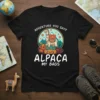 Black t-shirt with "Alpaca My Bags" text and a cartoon alpaca sitting on luggage, with mountains in the background