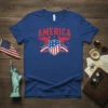 Royal blue t-shirt with "AMERICA" in red text above a shield with stars and stripes, flanked by red eagles and