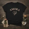 Black t-shirt with the word "AMORA" in arched pink lettering above a pink heart with a vine and leaves design