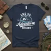 And So The Adventure Begins t-shirt with mountain and sun graphic, featuring white text on navy blue fabric