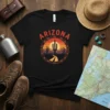 Arizona text graphic with a desert sunset, saguaro cacti, mountains, and a winding road within a circular emblem
