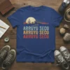 Arroyo Seco text in retro colors on a t-shirt with a desert sunset landscape graphic and cactus