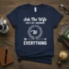 Ask The Wife SHE'S GOT ANSWERS to EVERYTHING quote on a navy blue t-shirt, featuring decorative wreath and arrow graphic
