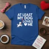 At Least My Dog Loves Me quote with a cute running dog and hearts on a blue t-shirt design