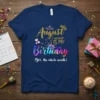 Navy blue t-shirt with "August IS MY Birthday (Yes, the whole month)" in glittery gold and rainbow tie-dye text, with