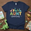AUNT saurus t-shirt design with colorful dinosaur letters and a playful script font below. Features cartoon dinosaurs across the top