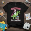 Black t-shirt with "AUNTICORN" and "It's an Alternative Perspective NOT a Bad Influence" text, featuring a unicorn riding a dinosaur