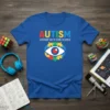 Blue t-shirt with "AUTISM A DIFFERENT WAY OF SEEING THE WORLD" text and a puzzle-piece eye graphic
