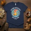 Autumn Adventures Rain or Shine T-Shirt with a cute fox character holding a mushroom umbrella in the rain, surrounded by