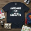 Navy t-shirt with "Awesome Like My Daughter" text in white and blue, featuring a shield graphic with father and daughter
