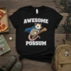 Awesome Possum T-Shirt featuring a cartoon possum in a superhero cape holding a slice of pizza. Text reads "AWESOME POSSUM"