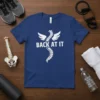 Blue t-shirt with "BACK AT IT" text and a white winged spine graphic, suitable for chiropractors and fitness recovery