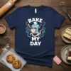 Bake My Day t-shirt design featuring a cute cartoon stand mixer with a chef's hat, whisk, and rolling pin