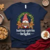 Navy t-shirt with "baking spirits bright" text, a Christmas gnome, and gingerbread cookies, set against a festive wreath