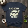 T-shirt with "Bao Down To Me!" text and a cartoon bao bun wearing sunglasses, food pun design