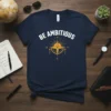 Navy t-shirt with white "BE AMBITIOUS" text and a golden compass graphic with sun rays