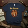 Be Brave text above a stylized lion head with constellations, on a navy blue t-shirt