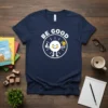 BE GOOD quote on a navy blue t-shirt with a cartoon sun giving a thumbs up and holding a lightbulb