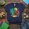 Navy blue t-shirt with colorful puzzle circle graphic and "be KIND" text, promoting autism awareness