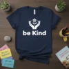 Navy blue t-shirt with white "be Kind" text and a graphic of hands holding a sprouting flower