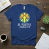 Blue t-shirt with "BE POSITIVE Joshua 1:9" text and a circular graphic of an upward arrow with sun rays