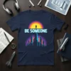 Be Someone t-shirt with a stylized city skyline graphic and sunset motif. Motivational text displayed prominently