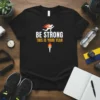 Black t-shirt with "BE STRONG THIS IS YOUR YEAR" text, a running figure with flames, and a torch graphic